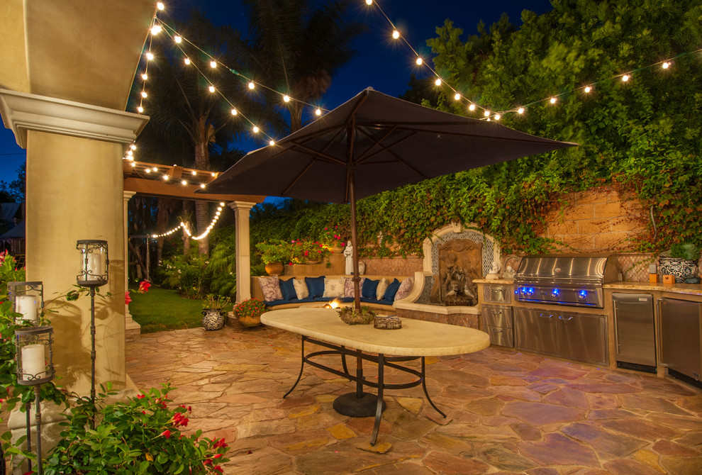 Photo of a mediterranean patio in Los Angeles with an outdoor kitchen, natural stone pavers and no cover.