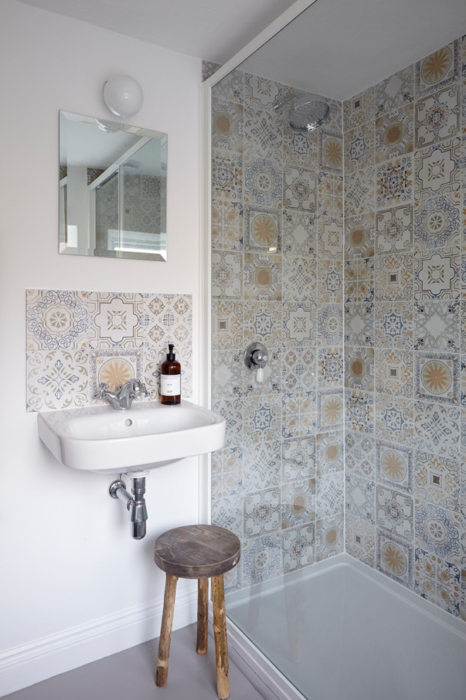Mid-sized bathroom in Devon with an open shower, a wall-mount toilet, multi-coloured tile, ceramic tile, white walls, painted wood floors, a wall-mount sink, grey floor and a sliding shower screen.