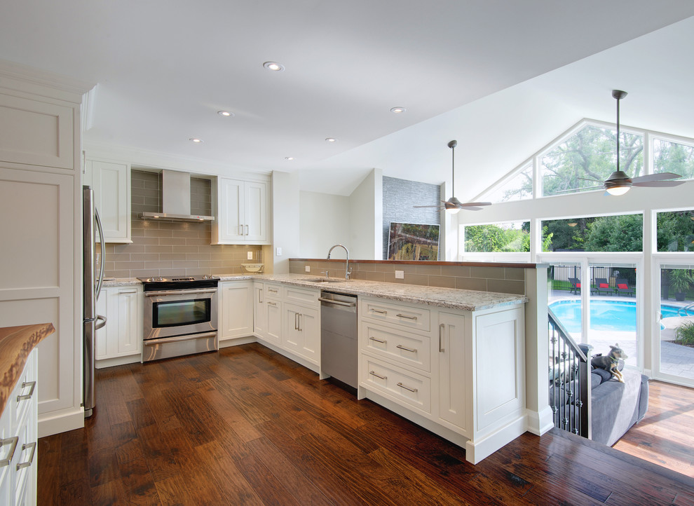 Mid-sized transitional u-shaped medium tone wood floor open concept kitchen photo in Toronto with an undermount sink, shaker cabinets, wood countertops, gray backsplash, glass tile backsplash, stainless steel appliances and an island