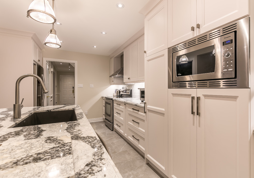 Inspiration for a large transitional gray floor enclosed kitchen remodel in Toronto with an undermount sink, recessed-panel cabinets, white cabinets, quartz countertops, white backsplash, ceramic backsplash, stainless steel appliances and an island