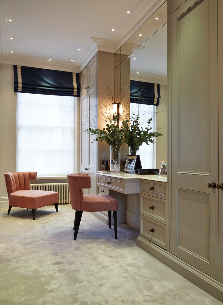 Traditional gender-neutral dressing room in London with recessed-panel cabinets, beige cabinets, carpet and beige floor.