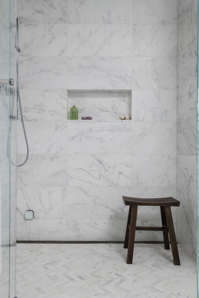 Large transitional master bathroom in New York with furniture-like cabinets, white cabinets, a freestanding tub, a curbless shower, a one-piece toilet, white tile, marble, grey walls, marble floors, an undermount sink, marble benchtops, grey floor, a hinged shower door and white benchtops.