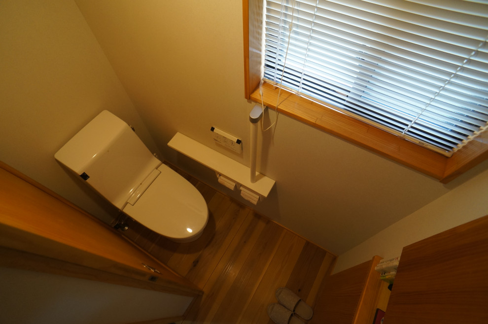 Aménagement d'un WC et toilettes asiatique de taille moyenne avec WC à poser, un mur blanc, un sol en bois brun, un sol marron et un plafond en bois.