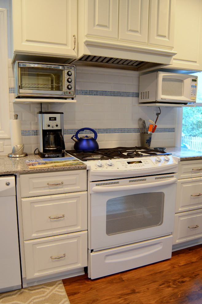 This is an example of a large country galley eat-in kitchen in Atlanta with a double-bowl sink, raised-panel cabinets, white cabinets, quartz benchtops, white splashback, subway tile splashback, white appliances, medium hardwood floors and multiple islands.