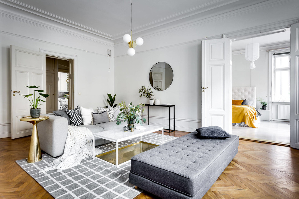 Photo of an expansive scandinavian enclosed living room in Stockholm with white walls, light hardwood floors and no tv.