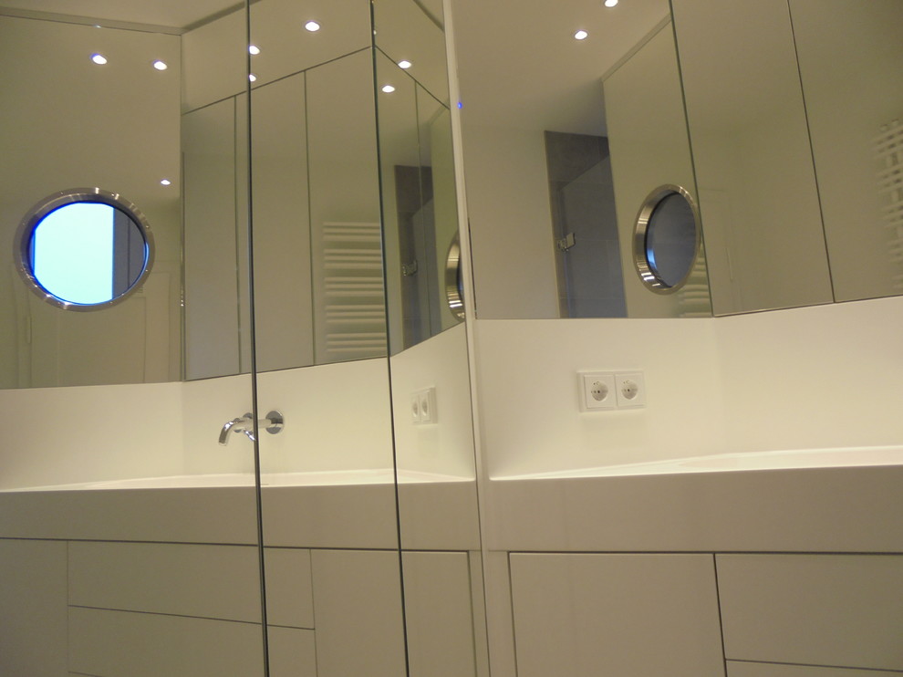 Duschbad With flächenbündigen Schrankfronten, weißen Schränken, Doppeldusche, Wandtoilette mit Spülkasten, grauen Fliesen, Keramikfliesen, grauer Wandfarbe, Keramikboden, Einbauwaschbecken, Mineralwerkstoff-Waschtisch, grauem Boden and weißer Waschtischplatte in Stuttgart