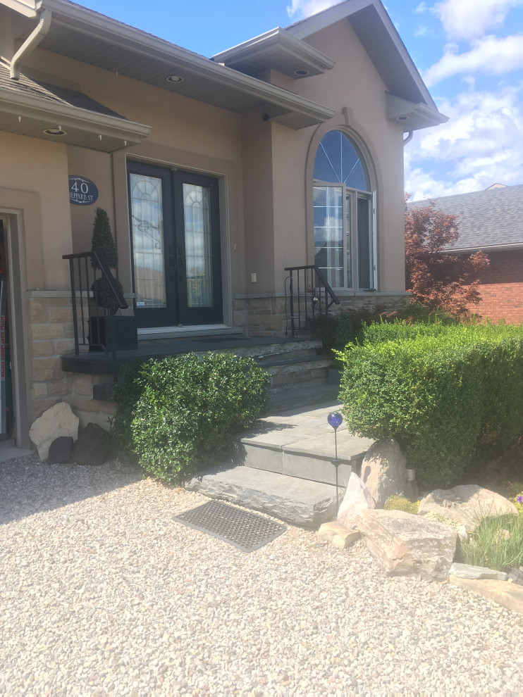 Design ideas for a mid-sized rustic rock and partial sun front yard stone driveway in Toronto.