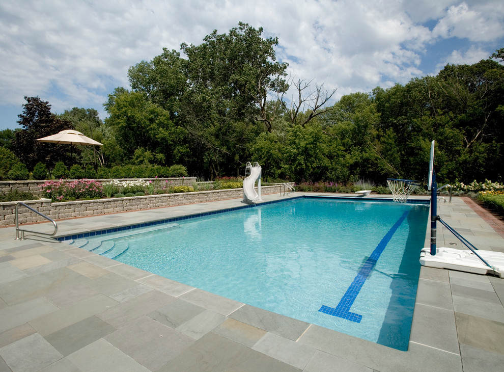 This is an example of a large country backyard rectangular lap pool in Chicago with natural stone pavers.