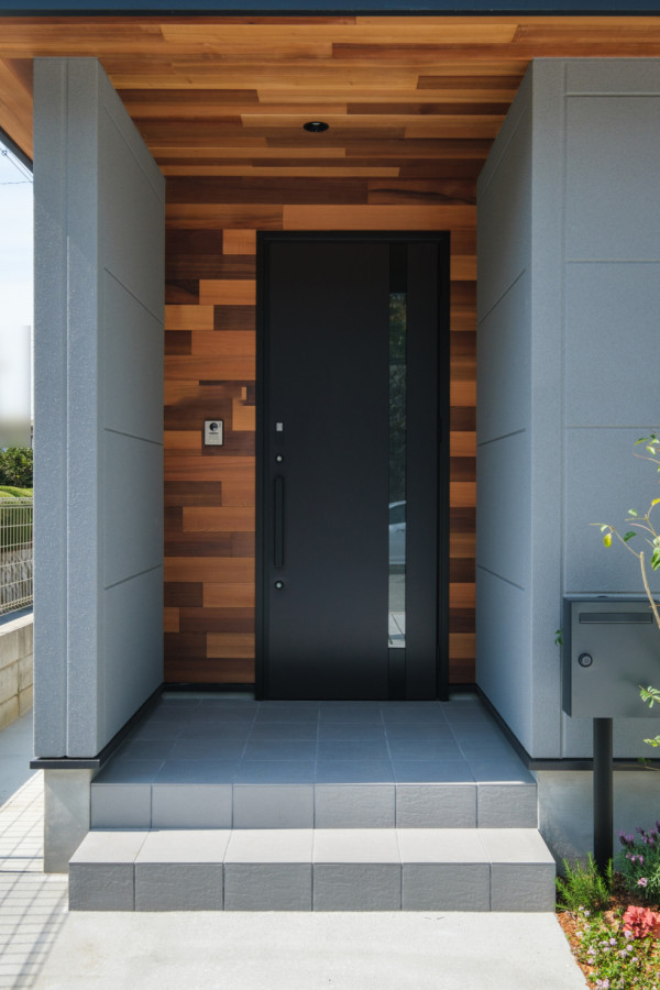 Foto på en entré, med en enkeldörr och en svart dörr