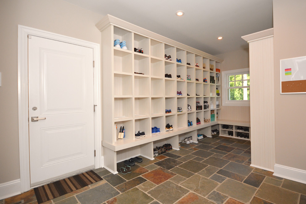 Large minimalist slate floor and brown floor entryway photo in New York with open cabinets and beige cabinets