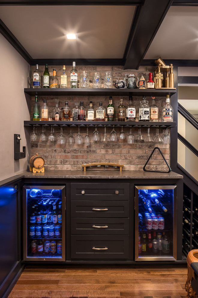 Inspiration for a mid-sized transitional single-wall home bar in Columbus with shaker cabinets, black cabinets, granite benchtops, multi-coloured splashback, brick splashback, medium hardwood floors, brown floor and brown benchtop.