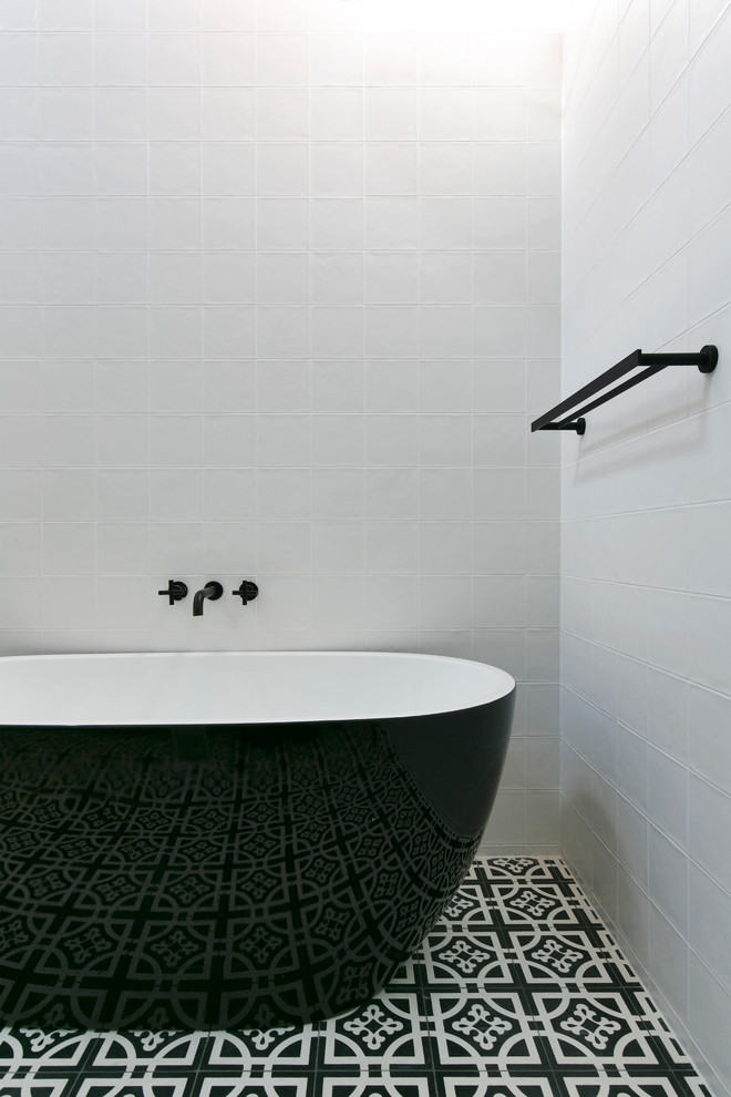 Design ideas for a contemporary master bathroom in Sydney with a freestanding tub, white walls and black floor.