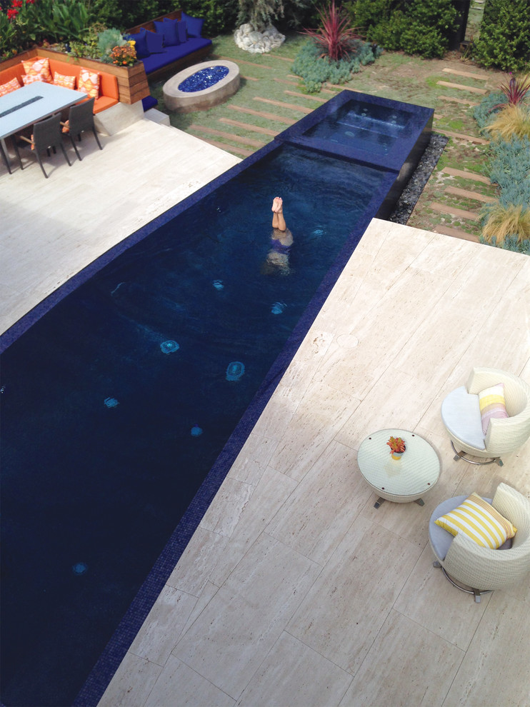 Inspiration for a mid-sized modern backyard custom-shaped infinity pool in Los Angeles with a hot tub and natural stone pavers.