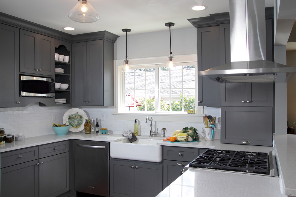 This is an example of a mid-sized transitional u-shaped eat-in kitchen in Milwaukee with a farmhouse sink, shaker cabinets, grey cabinets, white splashback, subway tile splashback, stainless steel appliances, dark hardwood floors, a peninsula, quartzite benchtops, brown floor and white benchtop.