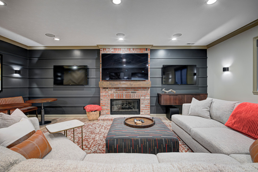 Mittelgroßes Modernes Untergeschoss mit Kamin, hellem Holzboden, Kaminumrandung aus Backstein, braunem Boden, Wandpaneelen und grauer Wandfarbe in Indianapolis