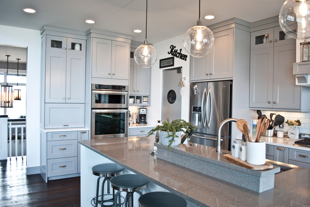 Open concept kitchen - large transitional l-shaped open concept kitchen idea with an undermount sink, flat-panel cabinets, gray cabinets, quartzite countertops, white backsplash, subway tile backsplash, stainless steel appliances and an island