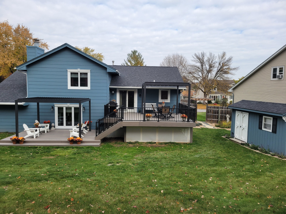 Large backyard ground level metal railing deck photo with a pergola