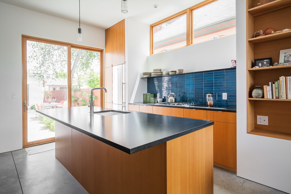Inspiration for a modern galley kitchen in Salt Lake City with an undermount sink, flat-panel cabinets, medium wood cabinets, stainless steel appliances, concrete floors, blue splashback and with island.
