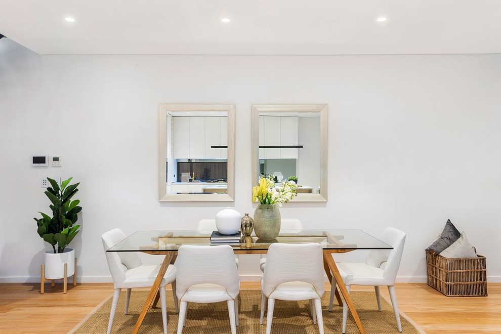 Photo of a contemporary open concept dining room in Sydney with white walls, light hardwood floors and a wall-mounted tv.