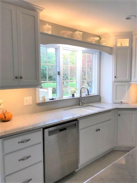 Kitchen - mid-sized transitional kitchen idea with flat-panel cabinets, an island, a double-bowl sink, white cabinets, quartz countertops, ceramic backsplash and stainless steel appliances