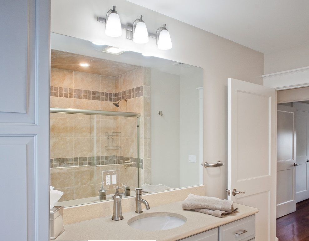 Inspiration for a small transitional 3/4 beige tile, gray tile and ceramic tile dark wood floor alcove bathtub remodel with raised-panel cabinets, white cabinets, a two-piece toilet, beige walls, an undermount sink and quartz countertops