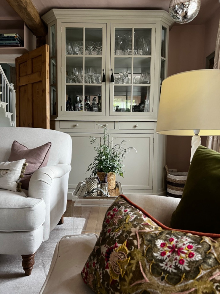 Imagen de salón cerrado de estilo de casa de campo de tamaño medio con paredes rosas, suelo de madera en tonos medios, marco de chimenea de ladrillo, suelo marrón, vigas vistas y cortinas