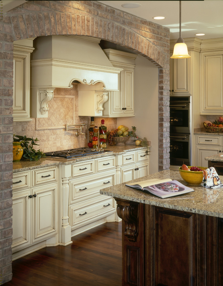 Inspiration for a large traditional u-shaped kitchen pantry in Minneapolis with an undermount sink, raised-panel cabinets, white cabinets, granite benchtops, travertine splashback, stainless steel appliances, medium hardwood floors and multiple islands.