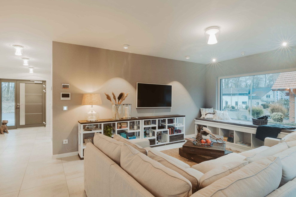 Geräumiges, Offenes Modernes Wohnzimmer ohne Kamin mit beiger Wandfarbe, Terrakottaboden, TV-Wand und beigem Boden in Sonstige