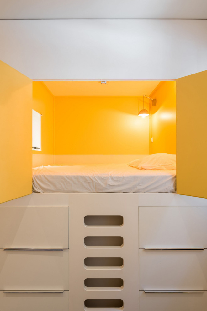 Small contemporary guest bedroom in Lyon with yellow walls, light hardwood floors and grey floor.