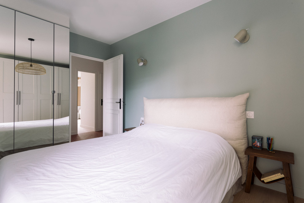 Réalisation d'une chambre parentale minimaliste de taille moyenne avec un mur bleu, parquet clair, aucune cheminée, un sol marron et dressing.