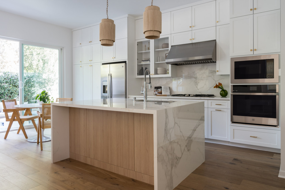 Design ideas for a mid-sized scandinavian eat-in kitchen in Los Angeles with an undermount sink, shaker cabinets, white cabinets, marble benchtops, multi-coloured splashback, marble splashback, stainless steel appliances, light hardwood floors, with island, beige floor and multi-coloured benchtop.