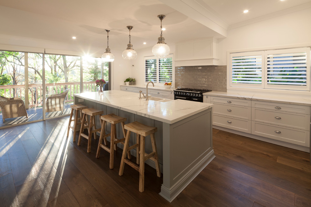 Contemporary single-wall open plan kitchen in Sydney with a farmhouse sink, flat-panel cabinets, white cabinets, stainless steel appliances, dark hardwood floors, with island and grey splashback.