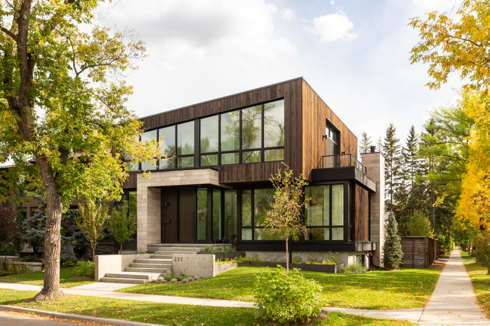 Design ideas for a large contemporary two-storey grey house exterior in Calgary with wood siding.
