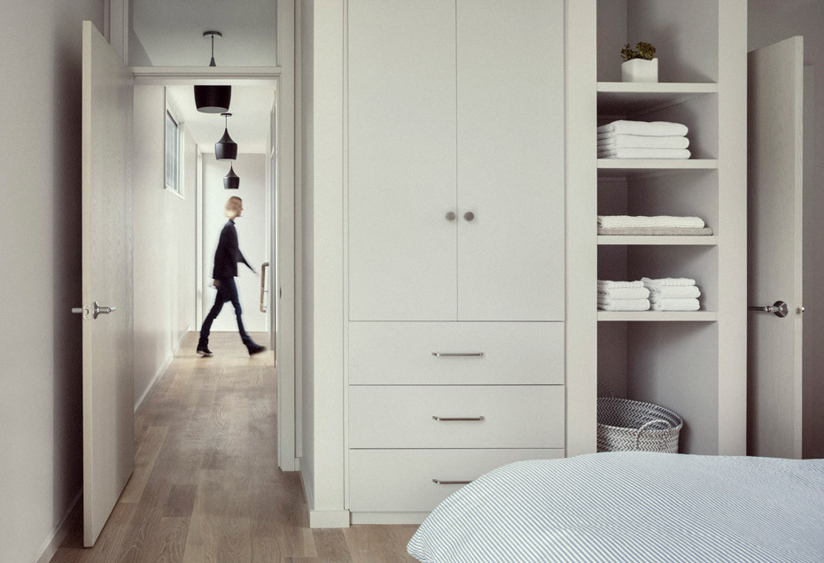Ejemplo de armario vestidor minimalista con armarios con paneles lisos, puertas de armario blancas y suelo de madera en tonos medios