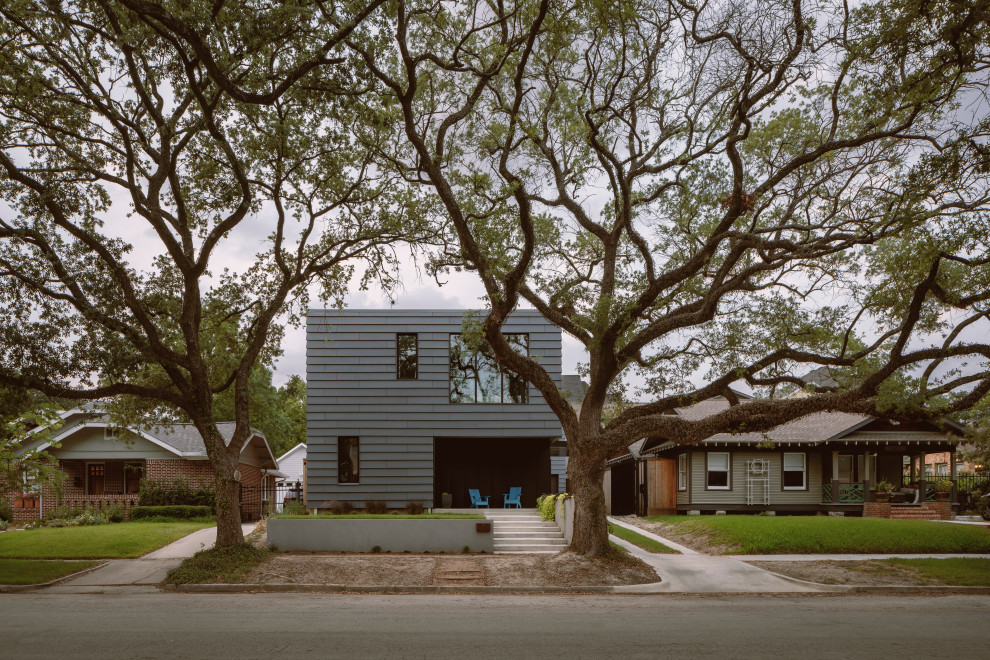 Photo of a mid-sized contemporary two-storey grey house exterior in Houston with concrete fiberboard siding, a gable roof, a metal roof, a black roof and clapboard siding.
