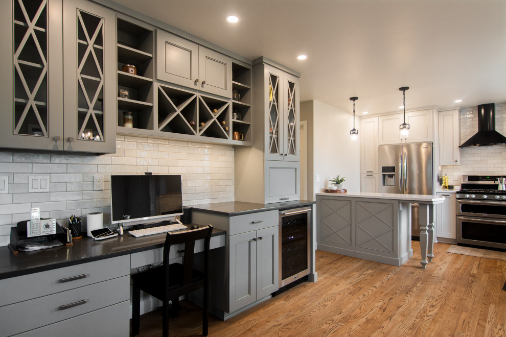 Inspiration for a mid-sized transitional l-shaped medium tone wood floor and brown floor kitchen remodel with an undermount sink, recessed-panel cabinets, gray cabinets, quartz countertops, white backsplash, ceramic backsplash, stainless steel appliances, a peninsula and white countertops