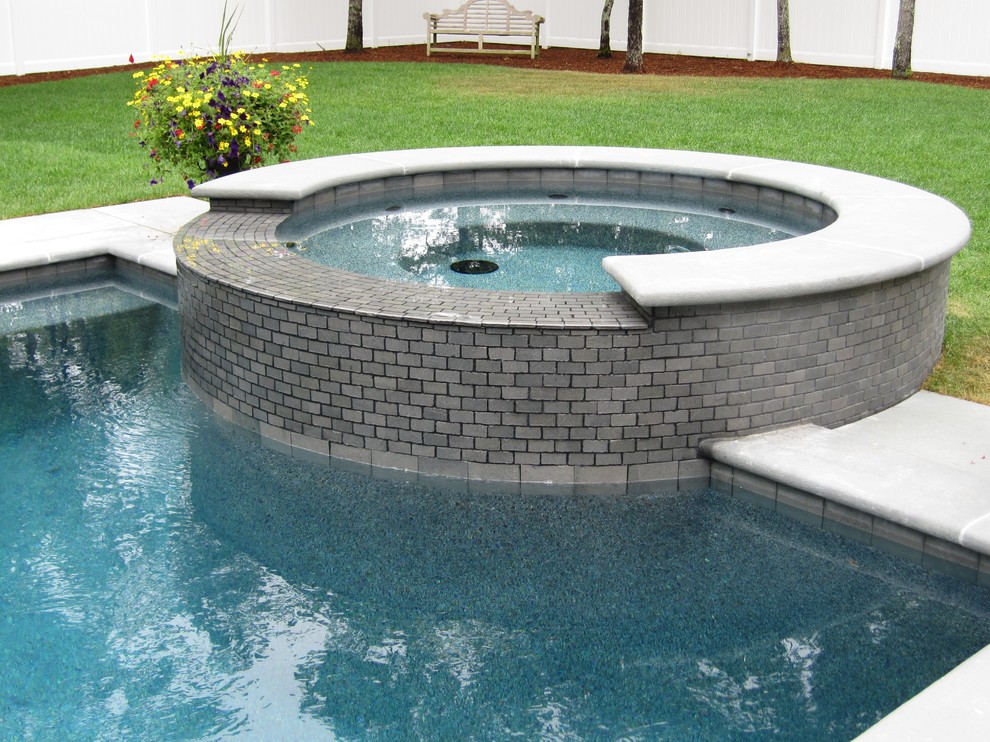 Traditional backyard pool in Boston with a hot tub and stamped concrete.