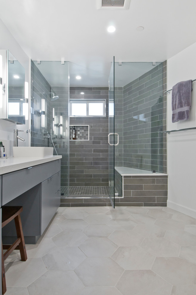 This is an example of a large contemporary master bathroom in Los Angeles with glass-front cabinets, grey cabinets, a corner shower, gray tile, porcelain tile, grey walls, cement tiles, a vessel sink, solid surface benchtops, grey floor, a hinged shower door and white benchtops.