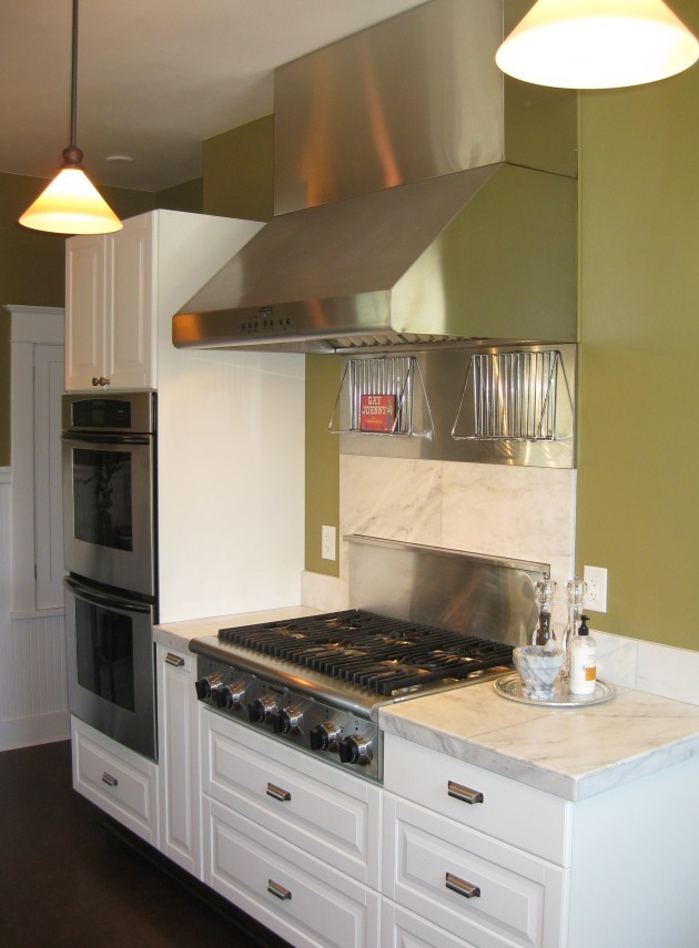 Photo of a small traditional u-shaped separate kitchen in Portland with raised-panel cabinets, white cabinets, marble benchtops, stainless steel appliances, cork floors, no island and brown floor.