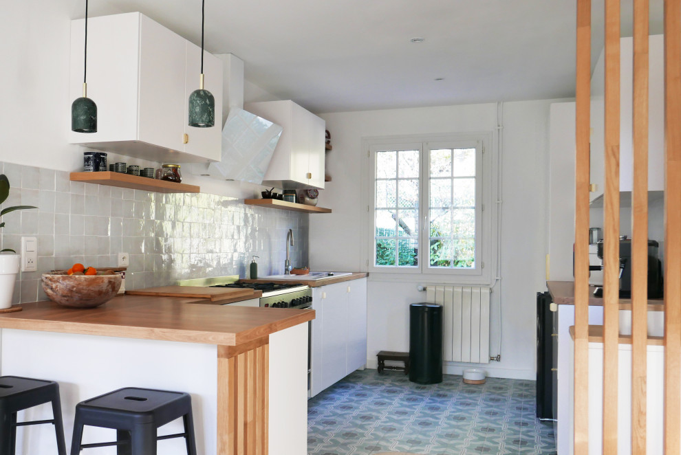 Inspiration for a mid-sized farmhouse l-shaped cement tile floor and green floor eat-in kitchen remodel in Marseille with a single-bowl sink, flat-panel cabinets, white cabinets, wood countertops, white backsplash, terra-cotta backsplash and a peninsula