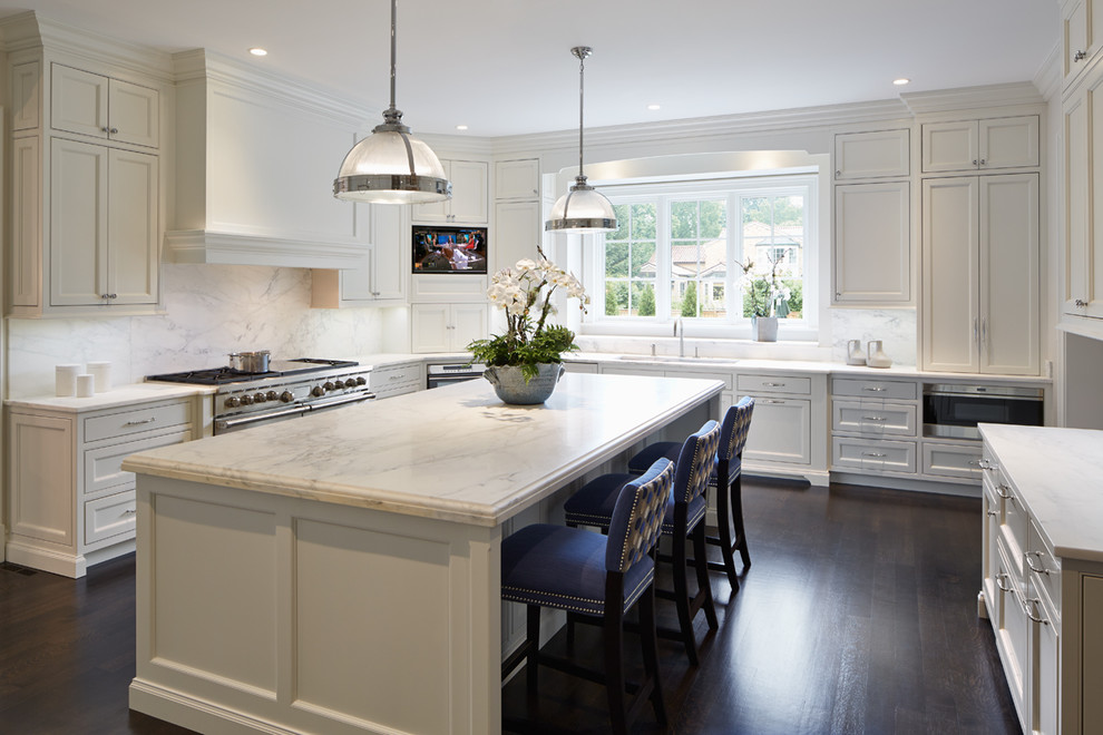 This is an example of a transitional u-shaped kitchen in Chicago with an undermount sink, shaker cabinets, beige cabinets, marble benchtops, white splashback, stone slab splashback, stainless steel appliances, dark hardwood floors and with island.