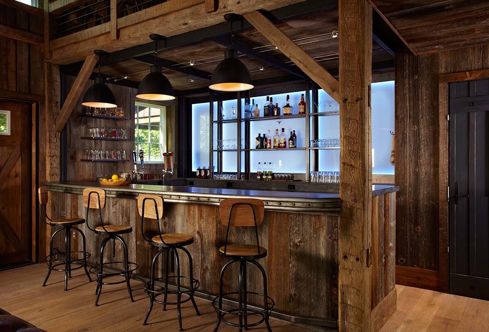 This is an example of a country u-shaped home bar in New York with medium hardwood floors, dark wood cabinets and beige floor.