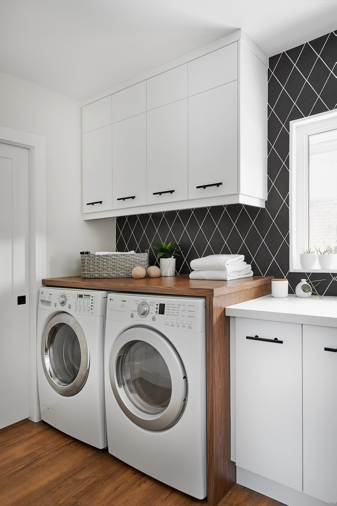 Inspiration for a contemporary single-wall dedicated laundry room in Toronto with flat-panel cabinets, white cabinets, white walls, medium hardwood floors, a side-by-side washer and dryer, brown floor and white benchtop.