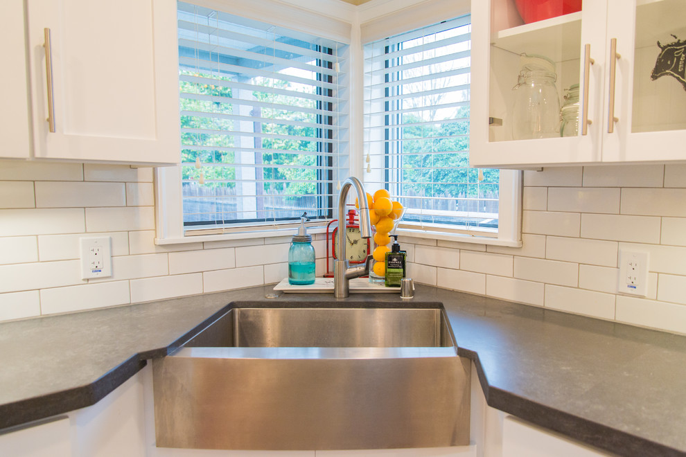 Inspiration for a transitional porcelain tile home design remodel in Sacramento with a farmhouse sink, shaker cabinets, white cabinets, white backsplash, subway tile backsplash, stainless steel appliances and an island
