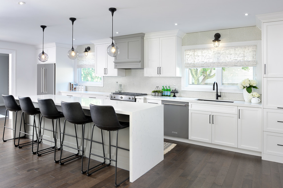 Kitchen - transitional dark wood floor and brown floor kitchen idea in Toronto with an undermount sink, shaker cabinets, white cabinets, white backsplash, stainless steel appliances, an island and white countertops