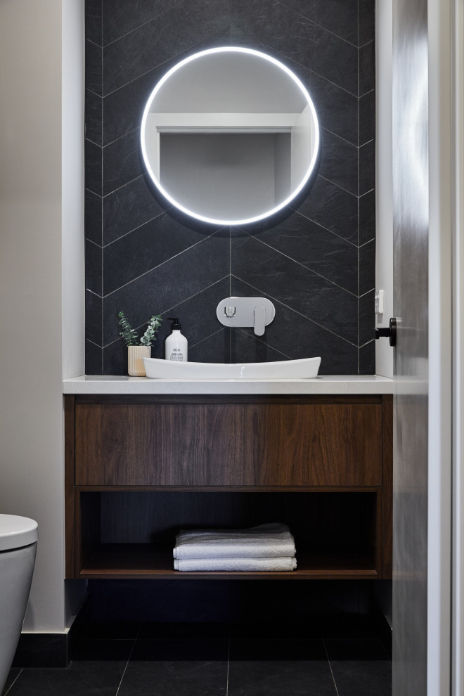Idées déco pour un WC et toilettes contemporain en bois foncé avec un carrelage noir, un sol gris et meuble-lavabo suspendu.