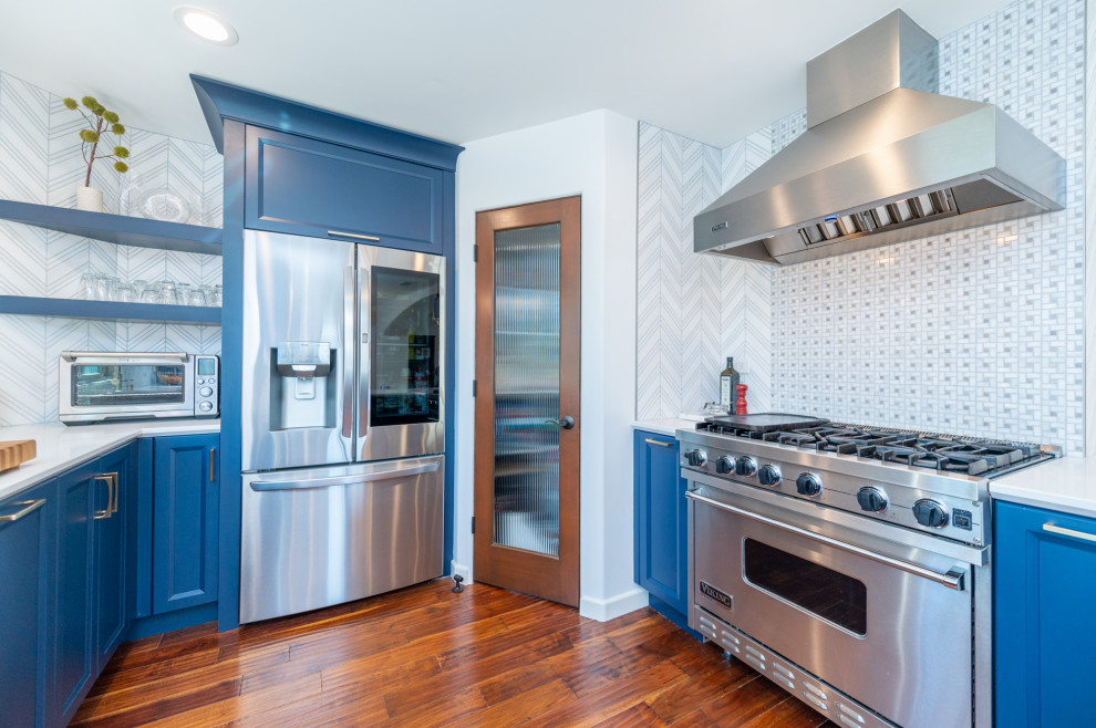 ロサンゼルスにあるラグジュアリーな広いトランジショナルスタイルのおしゃれなキッチン (エプロンフロントシンク、落し込みパネル扉のキャビネット、青いキャビネット、クオーツストーンカウンター、白いキッチンパネル、大理石のキッチンパネル、シルバーの調理設備、無垢フローリング、赤い床、白いキッチンカウンター) の写真