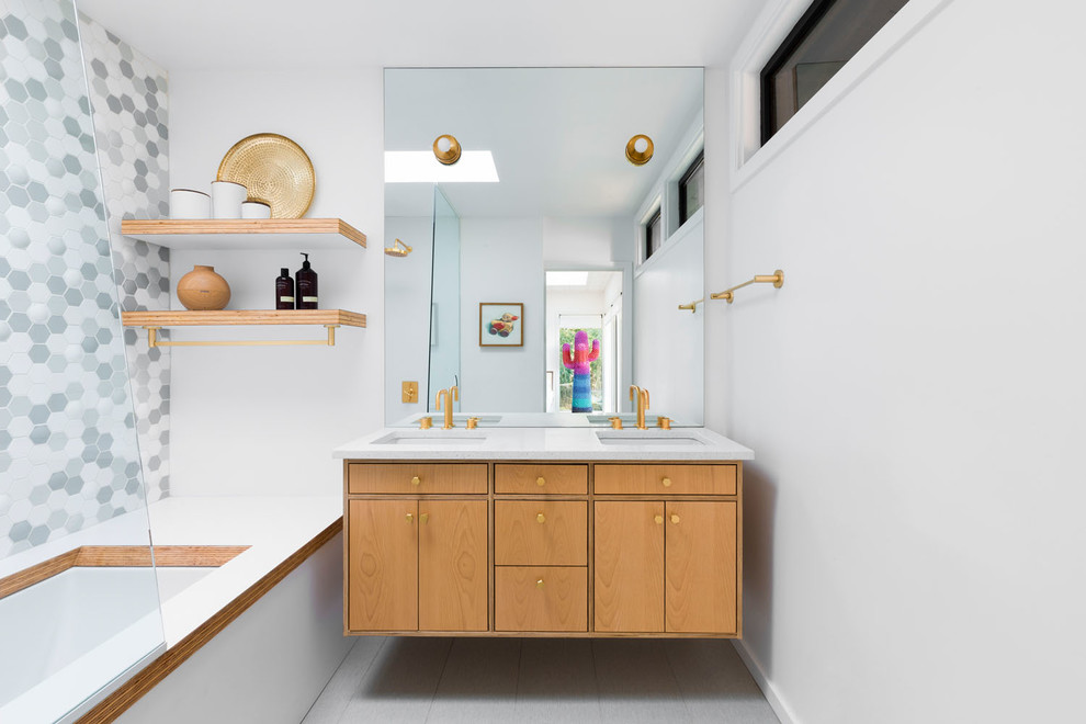 Mid-sized midcentury kids bathroom in Portland with flat-panel cabinets, light wood cabinets, an undermount tub, a shower/bathtub combo, gray tile, multi-coloured tile, white tile, mosaic tile, white walls, an undermount sink, solid surface benchtops, grey floor, an open shower and white benchtops.
