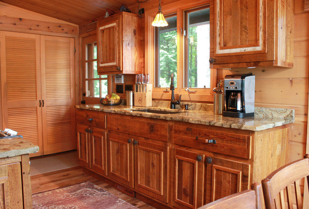 Eat-in kitchen - small rustic single-wall medium tone wood floor eat-in kitchen idea with a double-bowl sink, raised-panel cabinets, distressed cabinets, granite countertops, stainless steel appliances and an island
