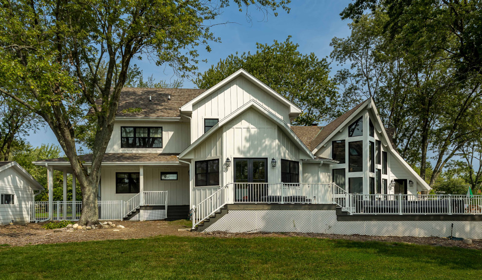 Photo of a large and white farmhouse two floor rear detached house in Chicago with concrete fibreboard cladding, a pitched roof, a shingle roof, a brown roof and board and batten cladding.